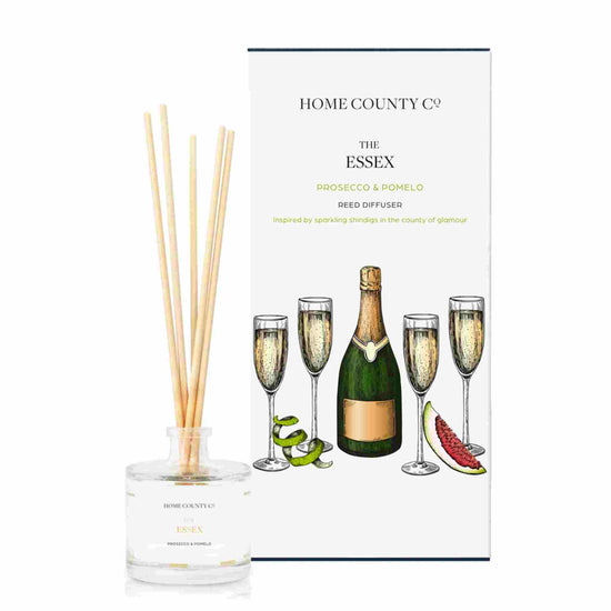 A prosecco and pomelo scented reed diffuser from Home County Co. The vegan friendly reed diffuser is shown next to the eco friendly reed diffuser box packaging.