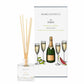 A prosecco and pomelo scented reed diffuser from Home County Co. The vegan friendly reed diffuser is shown next to the eco friendly reed diffuser box packaging.