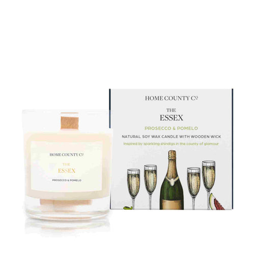 A prosecco and pomelo scented candle from Home County Co. The wooden wick soy candle is shown next to the eco friendly candle box packaging.