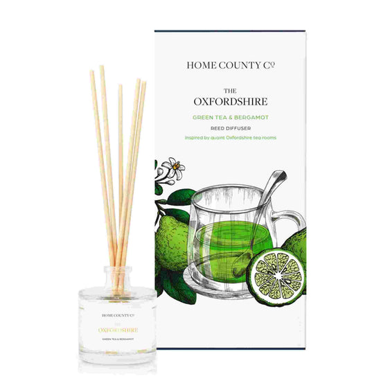 A green tea and bergamot scented reed diffuser from Home County Co. The vegan friendly reed diffuser is shown next to the eco friendly reed diffuser box packaging.
