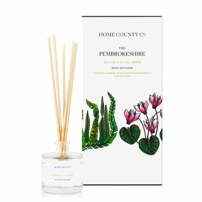 A sea kelp and cyclamen scented reed diffuser from Home County Co. The vegan friendly reed diffuser is shown next to the eco friendly reed diffuser box packaging.