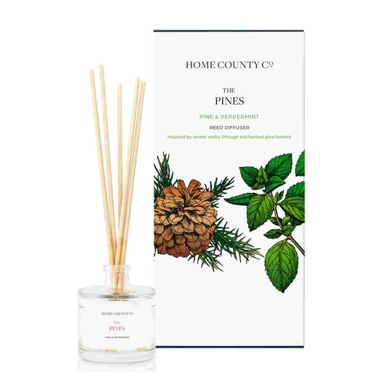 A pine and peppermint scented reed diffuser from Home County Co. The vegan friendly reed diffuser is shown next to the eco friendly reed diffuser box packaging.
