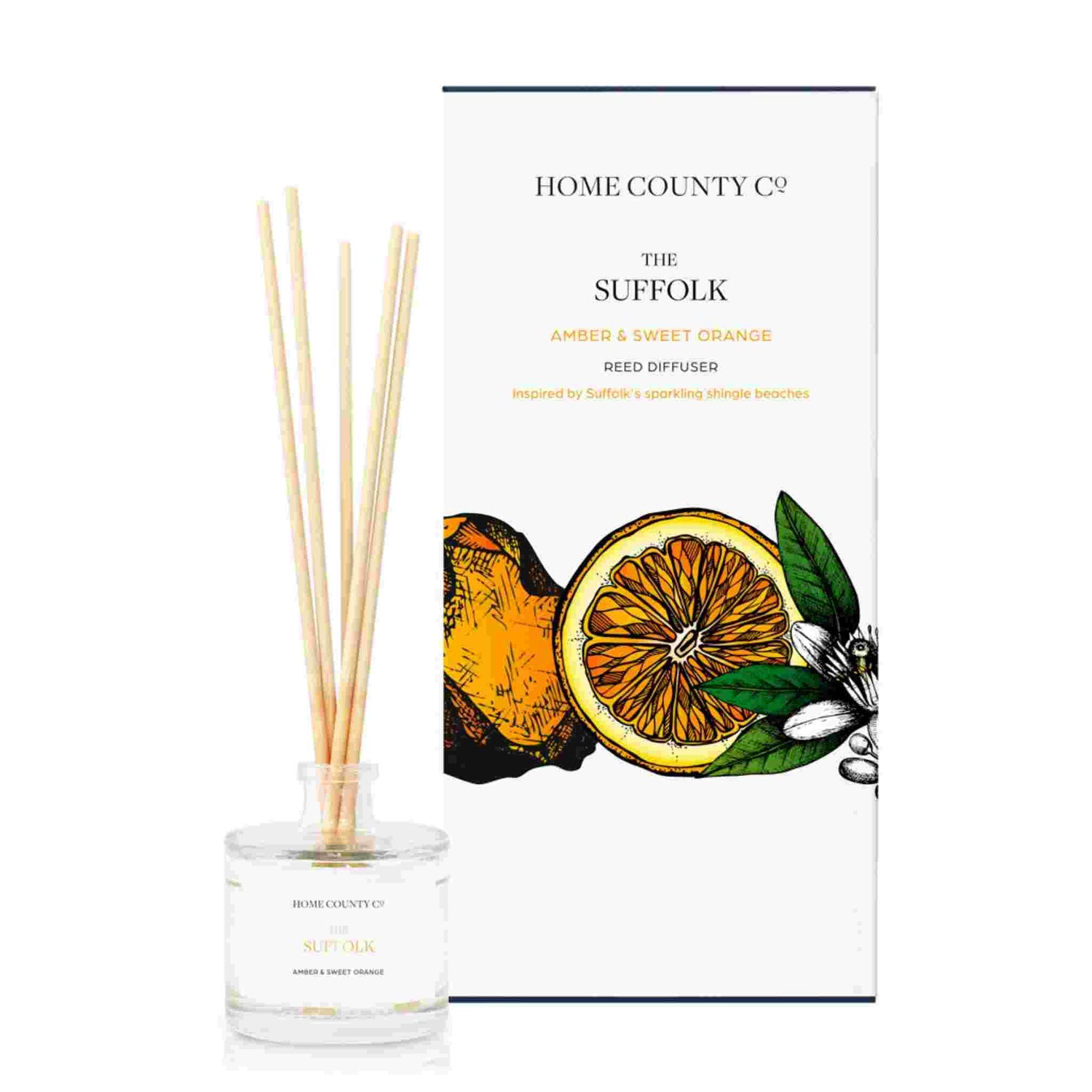 An amber and sweet orange scented reed diffuser from Home County Co. The vegan friendly reed diffuser is shown next to the eco friendly reed diffuser box packaging.
