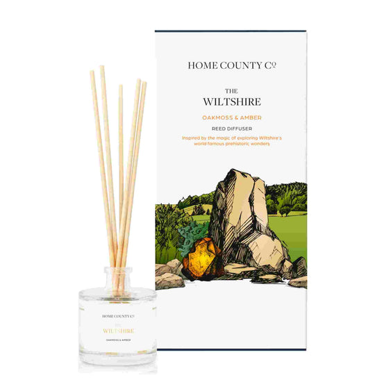 An oakmoss and amber scented reed diffuser from Home County Co. The vegan friendly reed diffuser is shown next to the eco friendly reed diffuser box packaging.