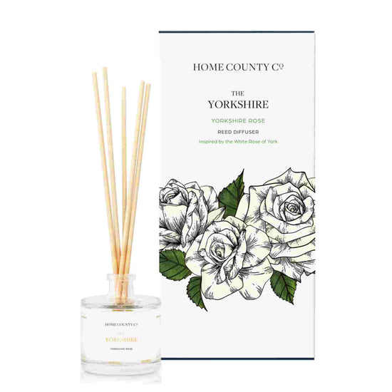 A Yorkshire rose scented reed diffuser from Home County Co. The vegan friendly reed diffuser is shown next to the eco friendly reed diffuser box packaging.