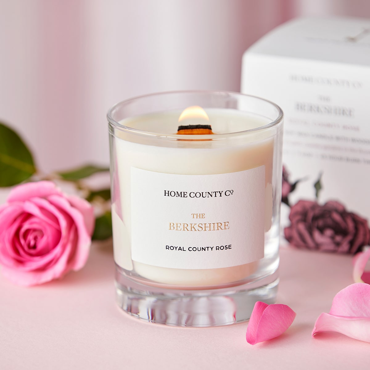 Home County Co. Berkshire rose scented candle shown with pink rose and candle packaging