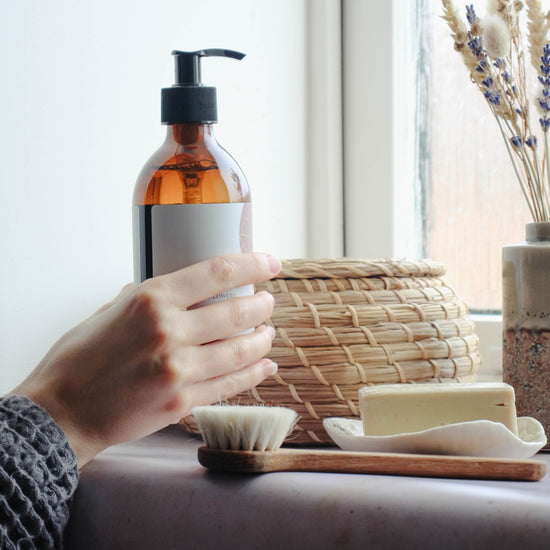 A person picks up a 300ml floral peony and wildflowers scented liquid hand wash in a bathroom