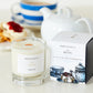 A Devon cream tea scented candle from the Home County Co. is shown next to its eco-friendly illustrated candle box