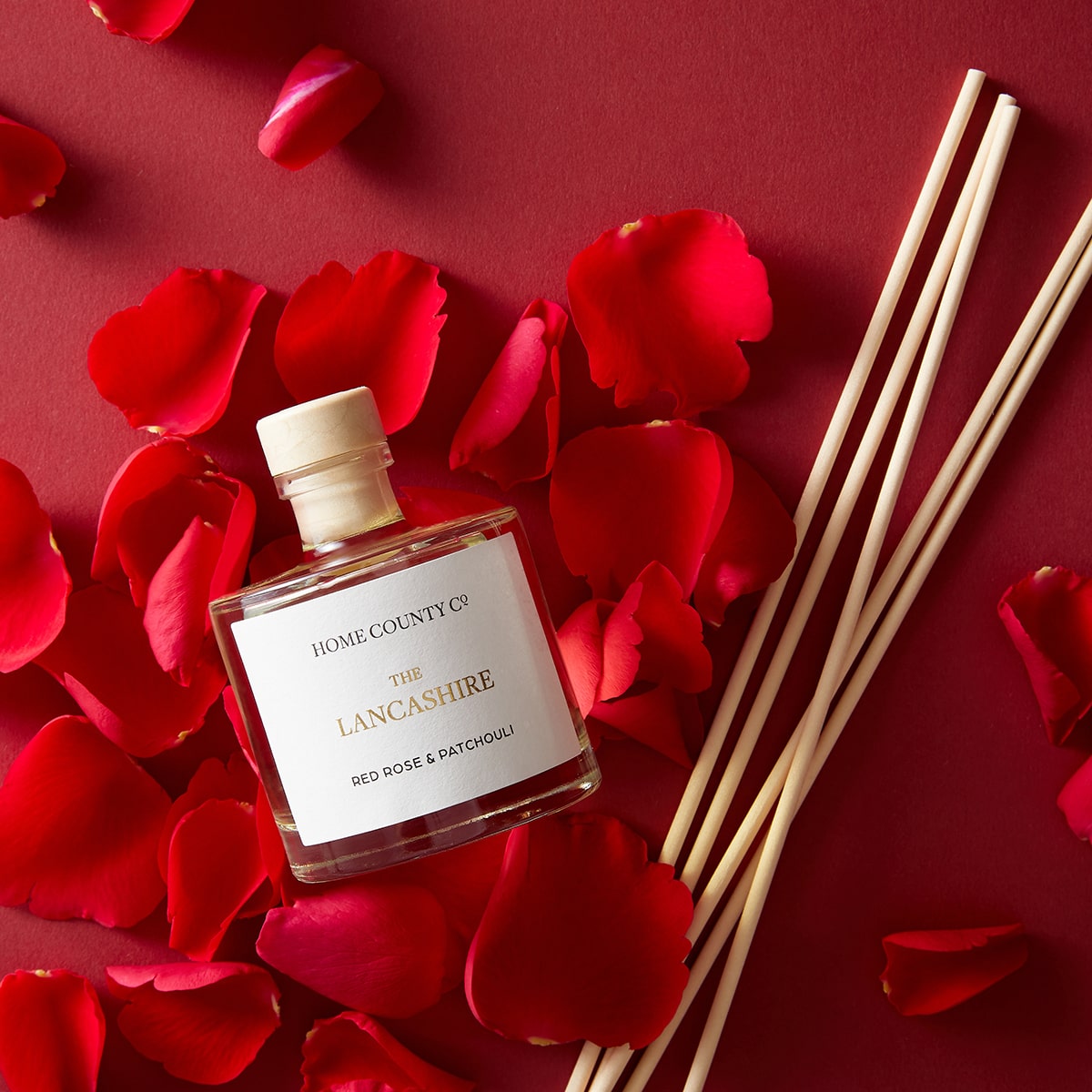 A Lancashire red rose and patchouli reed diffuser is shown with its porex reeds