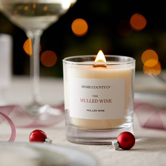 A Mulled Wine scented candle from the Home County Co. is shown alight on a Christmas table 