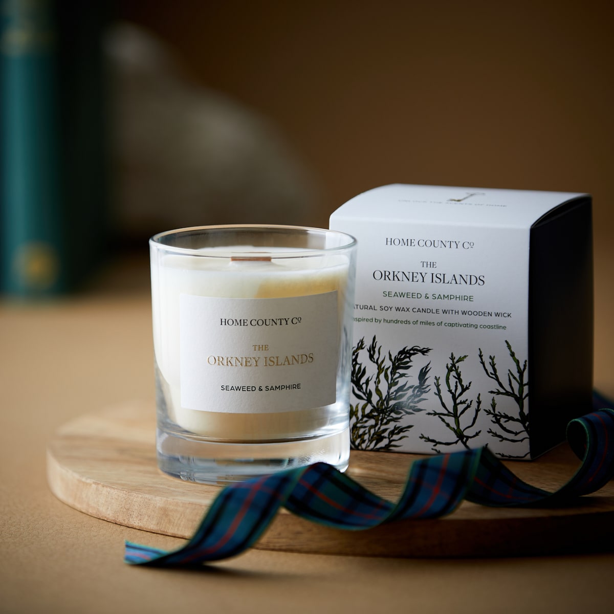 An Orkney Islands seaweed and samphire scented candle from the Home County Co is shown next to its illustrated candle packaging