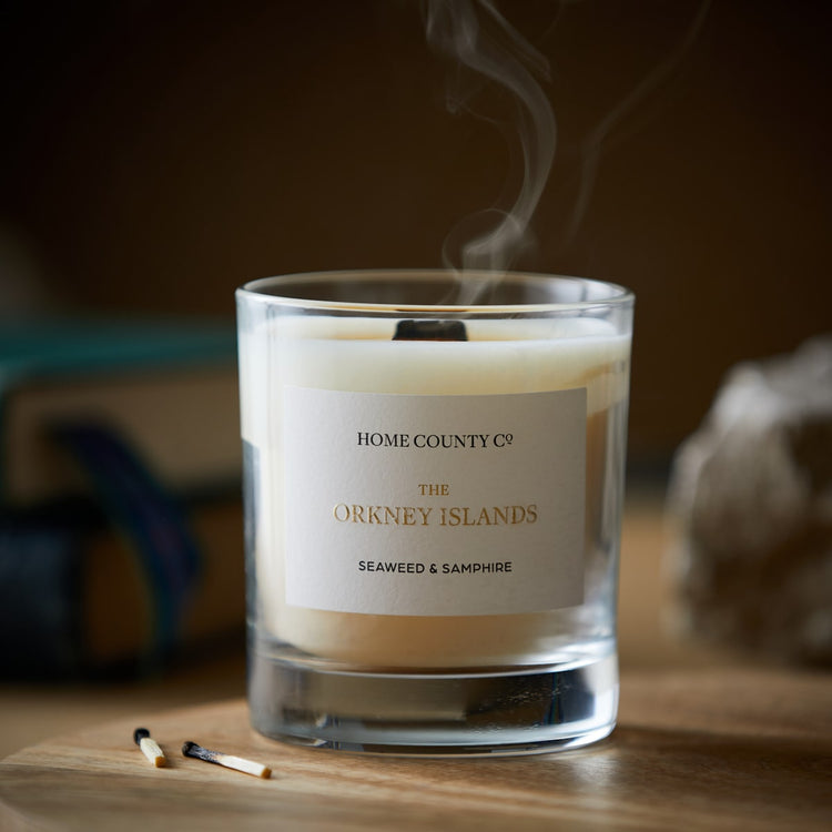 An Orkney Islands seaweed and samphire scented candle from the Home County Co is shown with its wooden wick blown out