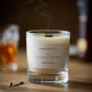A scotch whisky scented candle from the Home County Co is shown with its wooden wick blown out