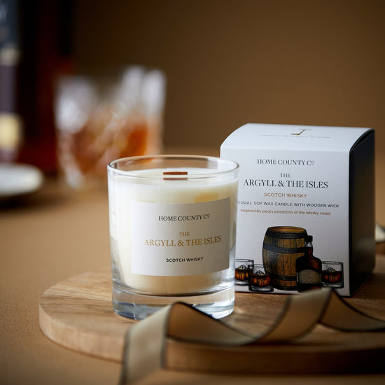 A scotch whisky scented candle from the Home County Co is shown with its eco-friendly packaging